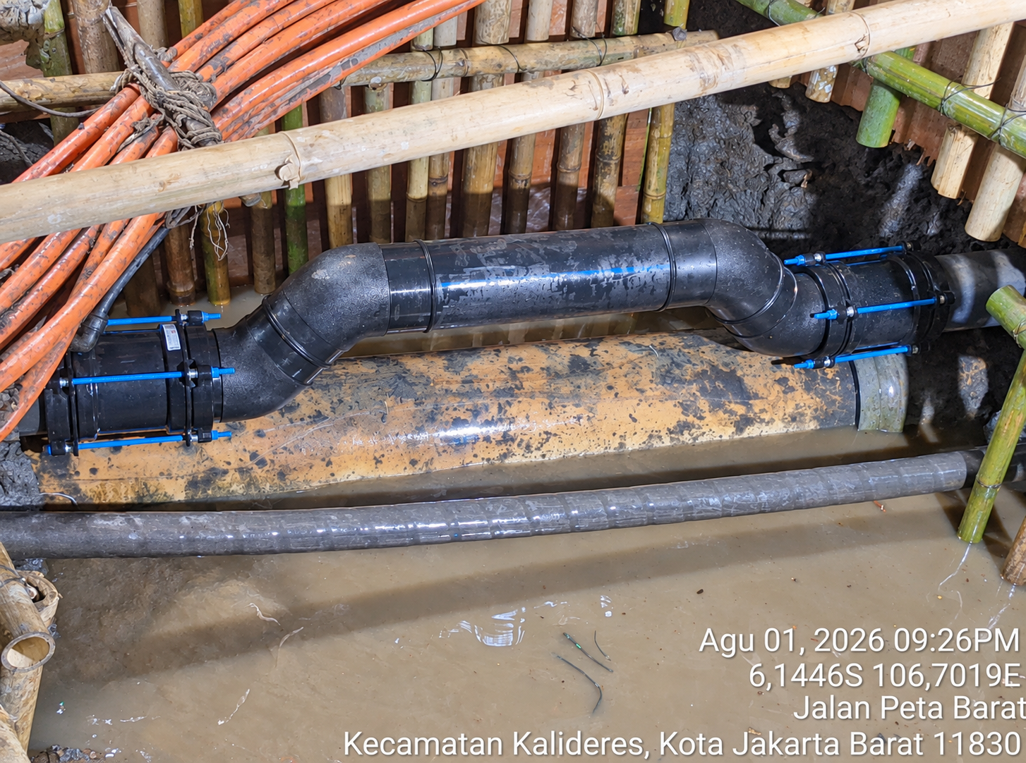 Black AquaFast couplings and pipework with blue bolts in a maintenance excavation